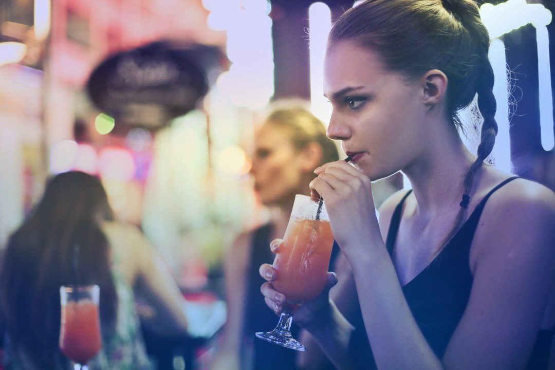 A woman drinking a beverage at a bar